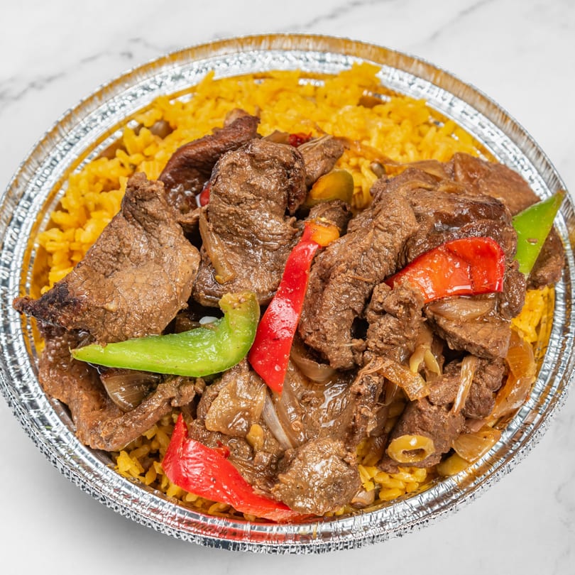 Dominican beef stew with red and green peppers, onions, and yellow rice in a foil container.