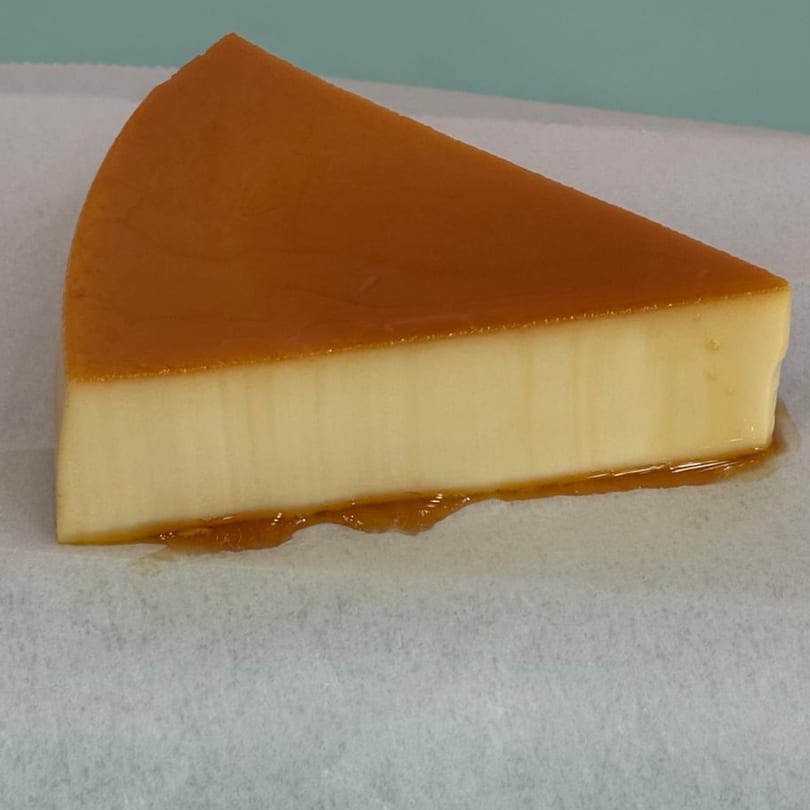 A slice of Dominican flan with golden caramel topping and a creamy yellow base.