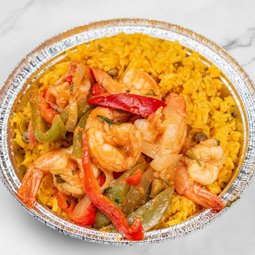 Dominican shrimp and yellow rice with red and green peppers in a foil container.