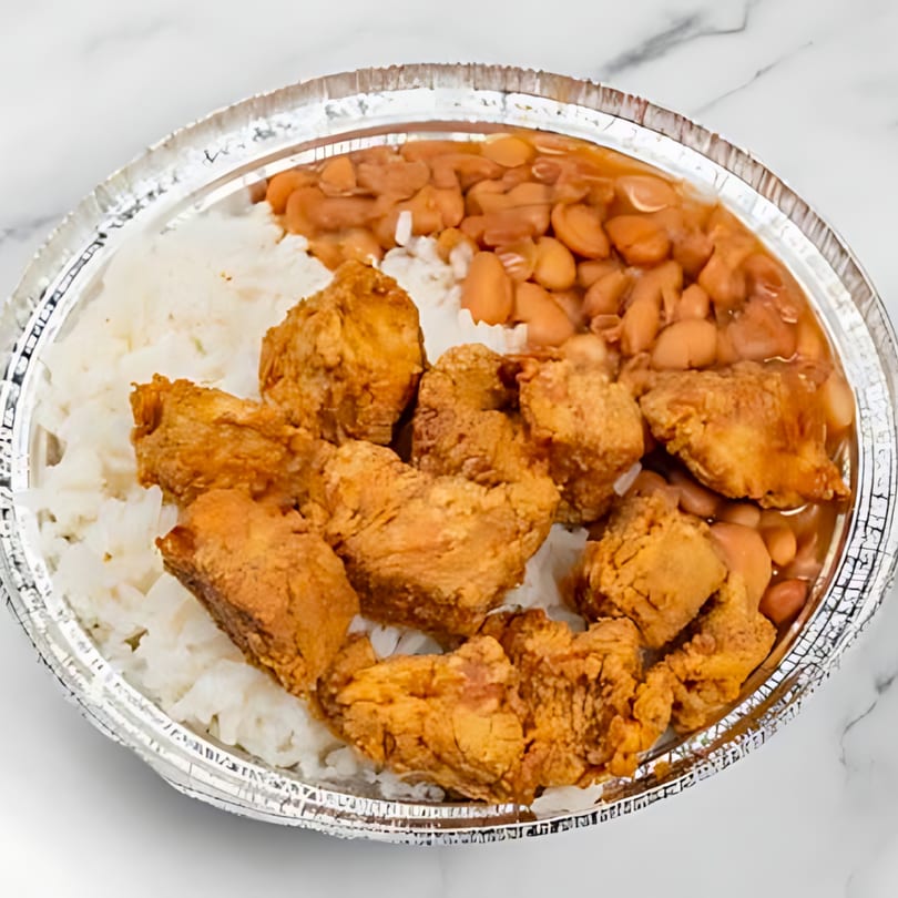 Dominican fried chicken, white rice, and beans in a foil takeout container.